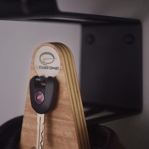 May include: A wooden key holder with a black key and a silver logo that says "OTHONE".