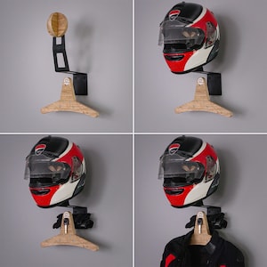 May include: A motorcycle helmet wall mount with a wooden hanger. The mount is black metal and has a hook for hanging a helmet. The hanger is made of wood and has a curved shape. The mount is shown with a red and white motorcycle helmet hanging on it.