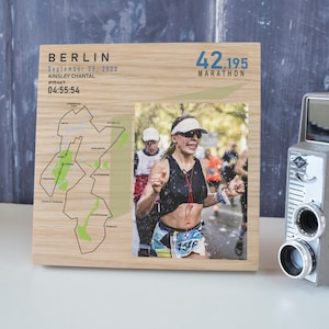 May include: Wooden framed photo with a map and text from the Berlin Marathon. The photo shows a runner in a race. The text includes "BERLIN", "September 25, 2022", "KINSLEY CHANTAL", "#15467", and "04:55:54".