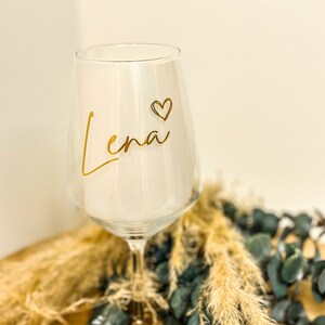 May include: A white ceramic mug with a black handle and the text "But First, Coffee" in a bold, black font. The mug is set against a blurred background, suggesting a cozy setting. The mug appears to be approximately 4 inches tall.