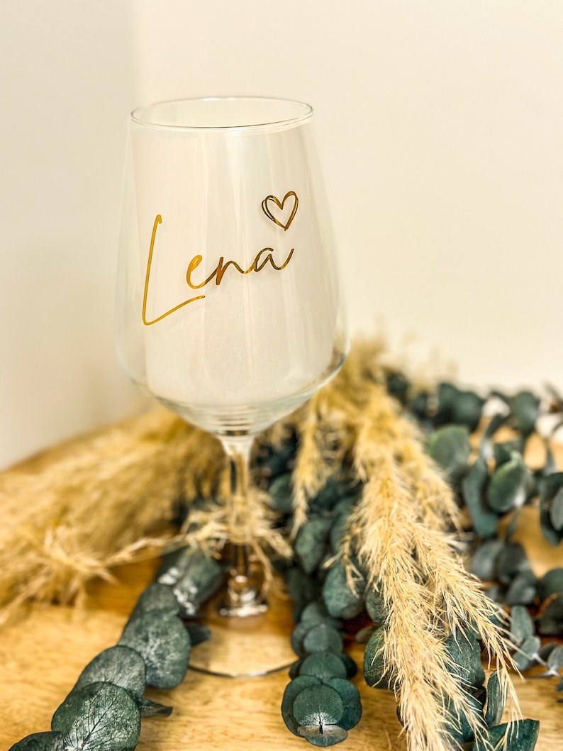 May include: A white ceramic mug with a black handle and the text "But First, Coffee" in a bold, black font. The mug is set against a blurred background, suggesting a cozy setting. The mug appears to be approximately 4 inches tall.