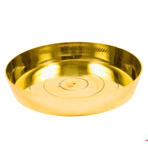 May include: A golden-colored, shallow bowl with a wide, curved rim. The bowl has a circular design in the center and is made of a shiny, reflective metal. The bowl is likely used for religious or decorative purposes.