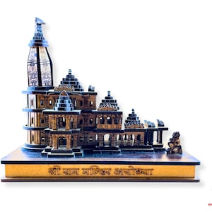 May include: A detailed wooden model of a temple with multiple levels and intricate carvings. The model is brown and tan, with a tower and several smaller structures. The base has text in a foreign language. A small statue is on the right.
