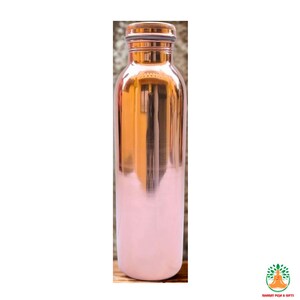 May include: A copper water bottle with a shiny, metallic finish. The top and cap are a darker copper color, while the bottom half is painted a soft pink. The bottle has a sleek, cylindrical shape.