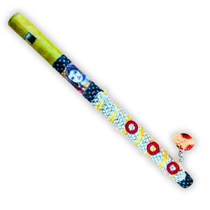 Puede incluir: Una flauta decorativa con cuerpo amarillo y diseño detallado. La flauta presenta un retrato de mujer, junto con patrones de círculos blancos, amarillos y rojos. Es un instrumento musical.