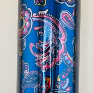May include: A blue water bottle with a paisley design in red, yellow, and white. The bottle has a shiny, metallic finish and a matching lid. This reusable bottle is great for staying hydrated.
