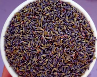 May include: A white bowl filled with dried lavender buds. The buds are a mix of purple and green.