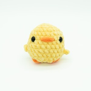 May include: A yellow crocheted chick toy with black eyes and an orange beak.