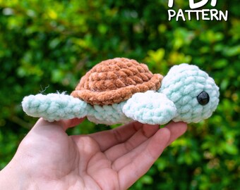 May include: A crocheted turtle amigurumi toy with a brown shell and a light green body. The toy is being held in a hand against a green background. The text "PDF PATTERN" is visible in the upper right corner of the image.