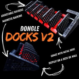 May include: Black and red DONGLE DOCKS V2 with adjustable dividers and magnetic backing. The product comes with metal rods and can be displayed on a desk or wall. The text "DONGLE DOCKS V2" is in orange.