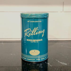 May include: A cylindrical teal metal tin with a lid, featuring the text 90 KOOLERETTES, Rilling, KOOLERWAVE, and RILLING COMPANY, NEW YORK, N.Y. printed in cream. A small oval seal with a star and the text Guaranteed by Good Housekeeping is visible.