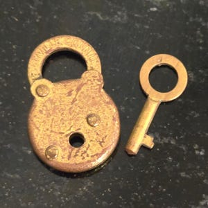 May include: A vintage brass padlock and key set. The padlock is round with the text "Terryville Conn. U.S.A." on the top. The key is a simple design with a circular handle.