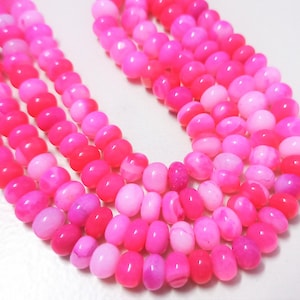 May include: A strand of pink and white agate beads. The beads are oval shaped and have a smooth, polished finish.