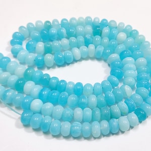 May include: A strand of light blue and white gemstone beads. The beads are round and have a smooth, polished finish.