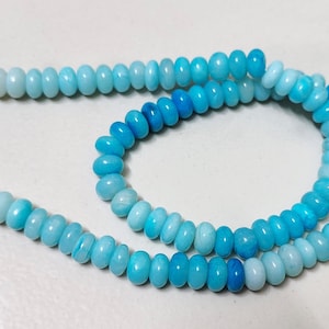 May include: A light blue and white ombre beaded necklace with a silver clasp.