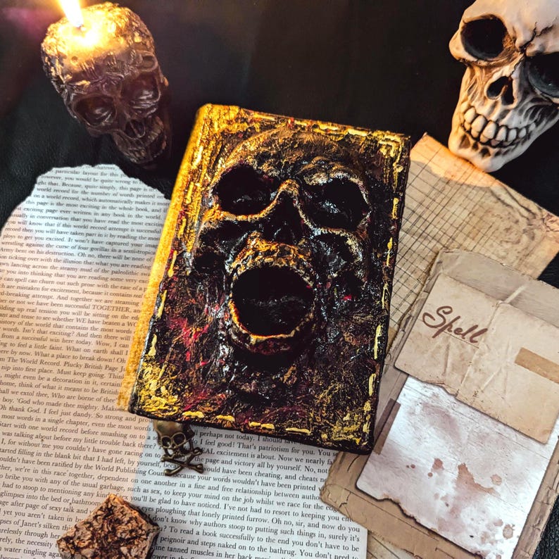 Occult spellbook with sculpted skull face cover, horror-style design on vintage papers