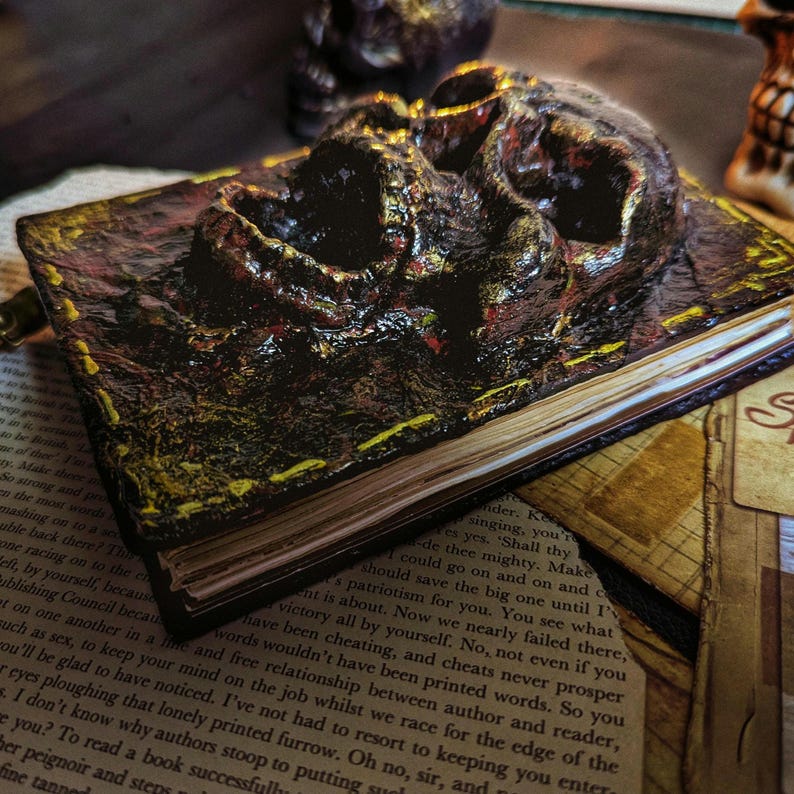 Occult spellbook with sculpted skull face cover, horror-style design on vintage papers