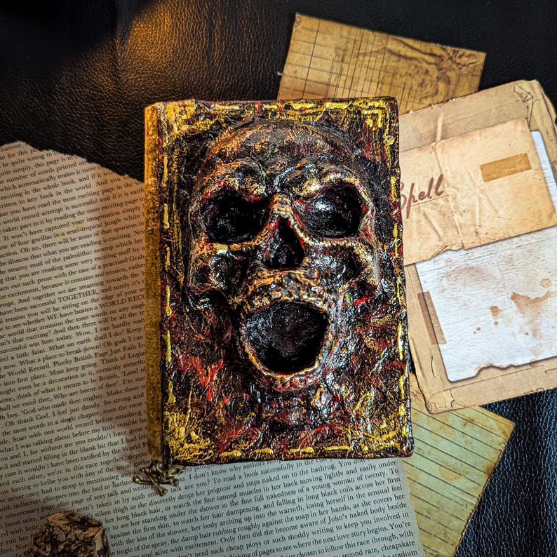 Occult spellbook with sculpted skull face cover, horror-style design on vintage papers