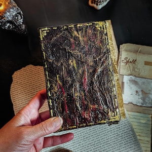 Occult spellbook with sculpted skull face cover, horror-style design on vintage papers