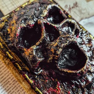 Occult spellbook with sculpted skull face cover, horror-style design on vintage papers