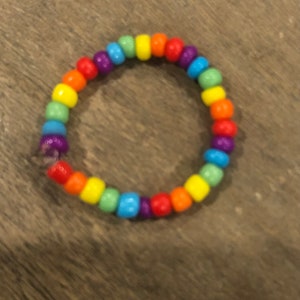 Pu&ograve; includere: Un braccialetto di perline arcobaleno con colori alternati di rosso, arancione, giallo, verde, blu, indaco e viola.