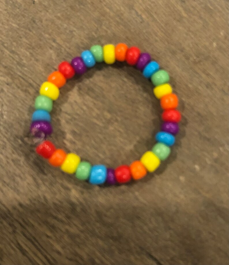 Pu&ograve; includere: Un braccialetto di perline arcobaleno con colori alternati di rosso, arancione, giallo, verde, blu, indaco e viola.