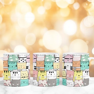 May include: Three white ceramic mugs with a colorful pattern of cartoon cats. The cats are wearing hats and have different expressions.