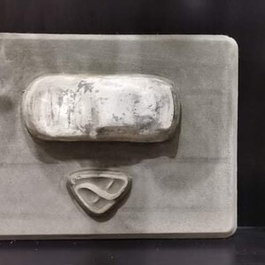 以下が含まれることがあります： 中央に盛り上がった銀色の長方形の形状を持つ灰色の長方形の型。長方形の下には、スタイリッシュな文字「S」のロゴが刻印されています。