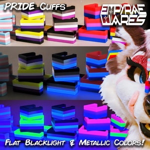 May include: Pride cuffs in a variety of colours, including black, white, yellow, blue, pink, and green. The cuffs are stacked in a tower formation. The image also shows a furry animal wearing a pride cuff on its head. The text "PRIDE CUFFS" and "EMPYRAE WARES" is visible in the image. The text "FLAT BLACKLIGHT & METALLIC COLORS!" is also visible in the image.