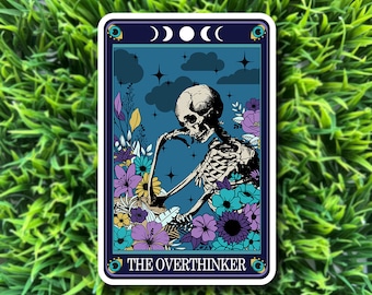 May include: A sticker featuring a skeleton sitting in a field of flowers with a blue background and stars. The text "THE OVERTHINKER" is at the bottom of the sticker.