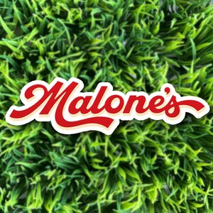 May include: A die-cut sticker featuring the word Malone's written in a bold, red, cursive script font with a cream-colored outline and a subtle drop shadow, positioned against a background of vibrant, textured green artificial grass blades.