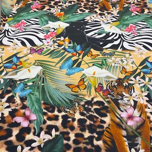 K&ouml;nnte beinhalten: Ein farbenfroher Stoff mit einem Dschungel-Druck, der schwarze Panther, Tiger, Schmetterlinge und tropische Pflanzen auf gelbem Hintergrund zeigt.