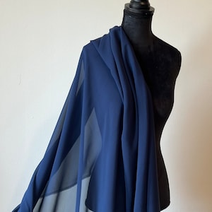 May include: A navy blue sheer fabric draped over a dress form. The fabric is lightweight and has a soft, flowing texture.