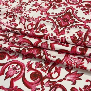 May include: White fabric with a red and pink floral damask pattern. The pattern features intricate swirls and leaves.