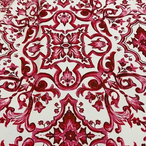 May include: White fabric with a repeating pattern of red and pink floral designs. The pattern is intricate and features a damask-like design.