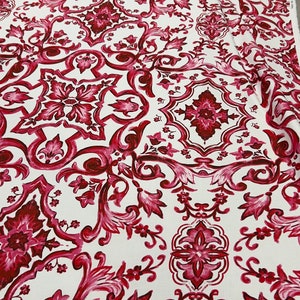 May include: Red and white fabric with a repeating pattern of intricate floral designs. The fabric has a vintage, damask-like feel.