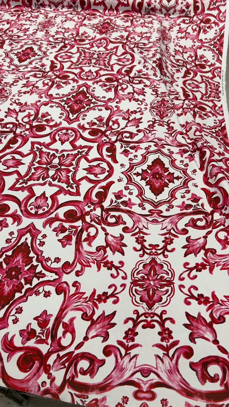 May include: Red and white fabric with a repeating pattern of intricate floral designs. The fabric has a vintage, damask-like feel.