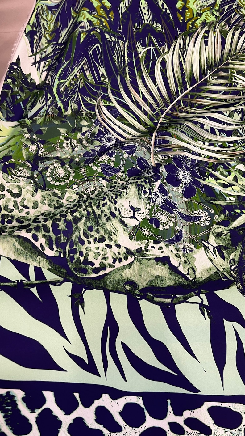Op de afbeelding: Stof met een jungle-thema. De stof heeft een luipaard, palmbladeren en bloempatronen in groen, wit en marineblauw. De onderkant van de stof heeft een zebra- en giraffenprint.
