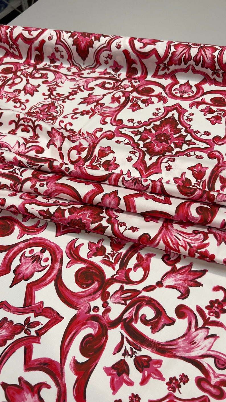 May include: White fabric with a red and pink floral damask pattern. The pattern features intricate swirls and leaves.