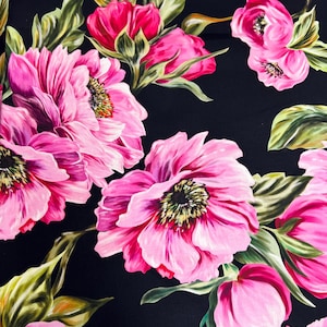 Op de afbeelding: Een zwarte stof met een roze bloemenpatroon. De bloemen zijn groot en hebben een gedetailleerd ontwerp. De stof is zacht en glad.