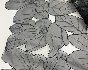 May include: Black sheer fabric with an embroidered floral design. The fabric features large, detailed magnolia flowers and leaves.