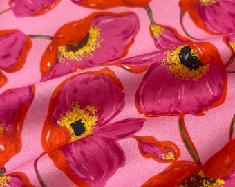 May include: Pink fabric with a repeating pattern of red and pink poppies. The poppies have yellow centers and are arranged in a random pattern.