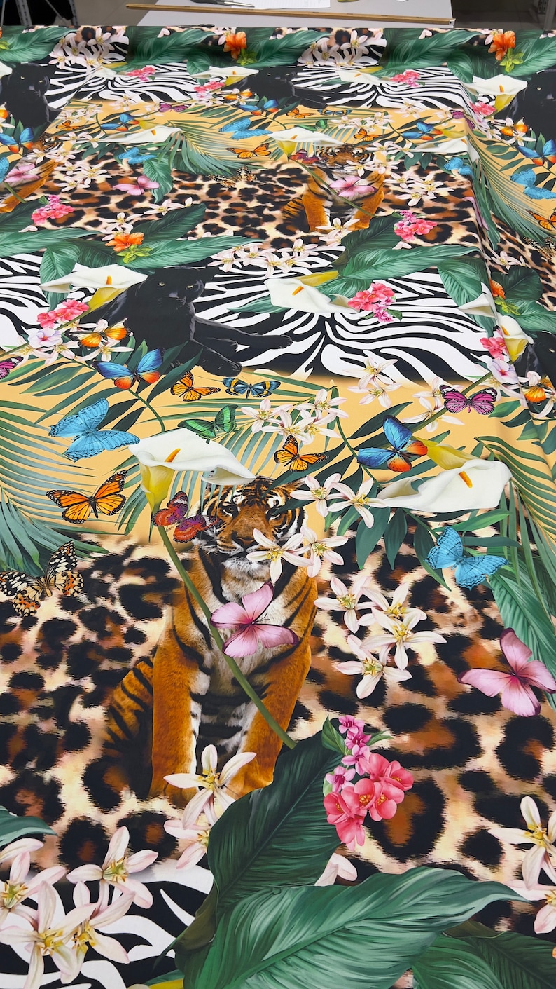 K&ouml;nnte beinhalten: Ein farbenfroher Stoff mit Dschungel-Motiv, auf dem ein Tiger, Zebra, Leopardenmuster, Schmetterlinge und tropische Pflanzen zu sehen sind.