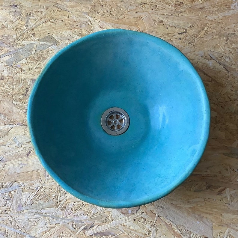 May include: A turquoise blue ceramic sink with a round shape and a chrome drain.