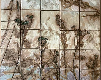 May include: A ceramic tile mural with a beige background and a pattern of brown and green pressed plants. The tile is divided into 16 squares.