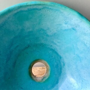 May include: A turquoise blue concrete sink with a round drain hole in the center.