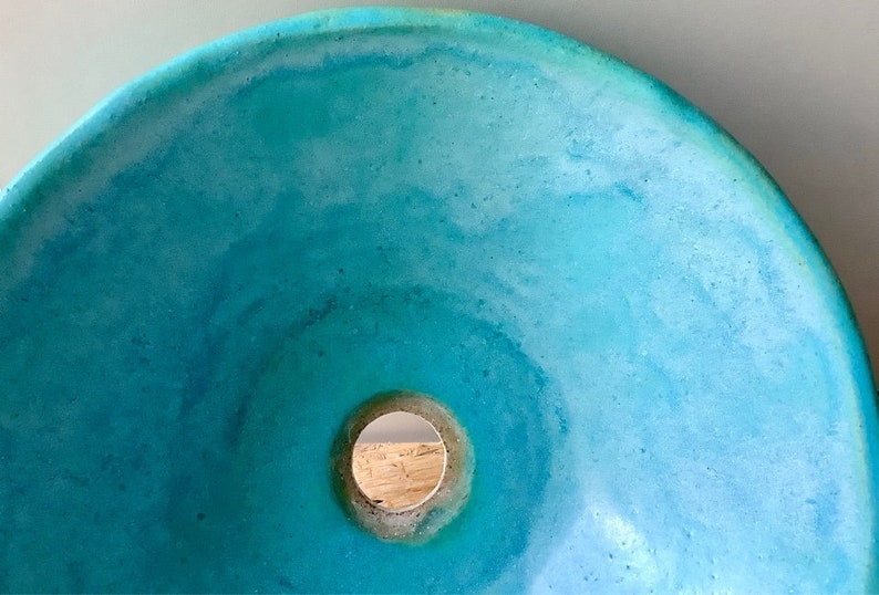 May include: A turquoise blue concrete sink with a round drain hole in the center.