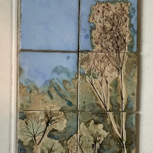 May include: A set of six square ceramic tiles arranged in a 2x3 grid. The tiles feature a nature-inspired design with a blue sky background and botanical elements in shades of beige, brown, and green. The artwork evokes a serene, natural aesthetic.