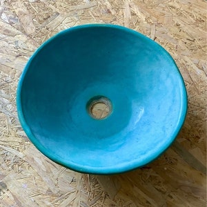 May include: A turquoise blue ceramic sink bowl with a round shape and a small drain hole in the center.
