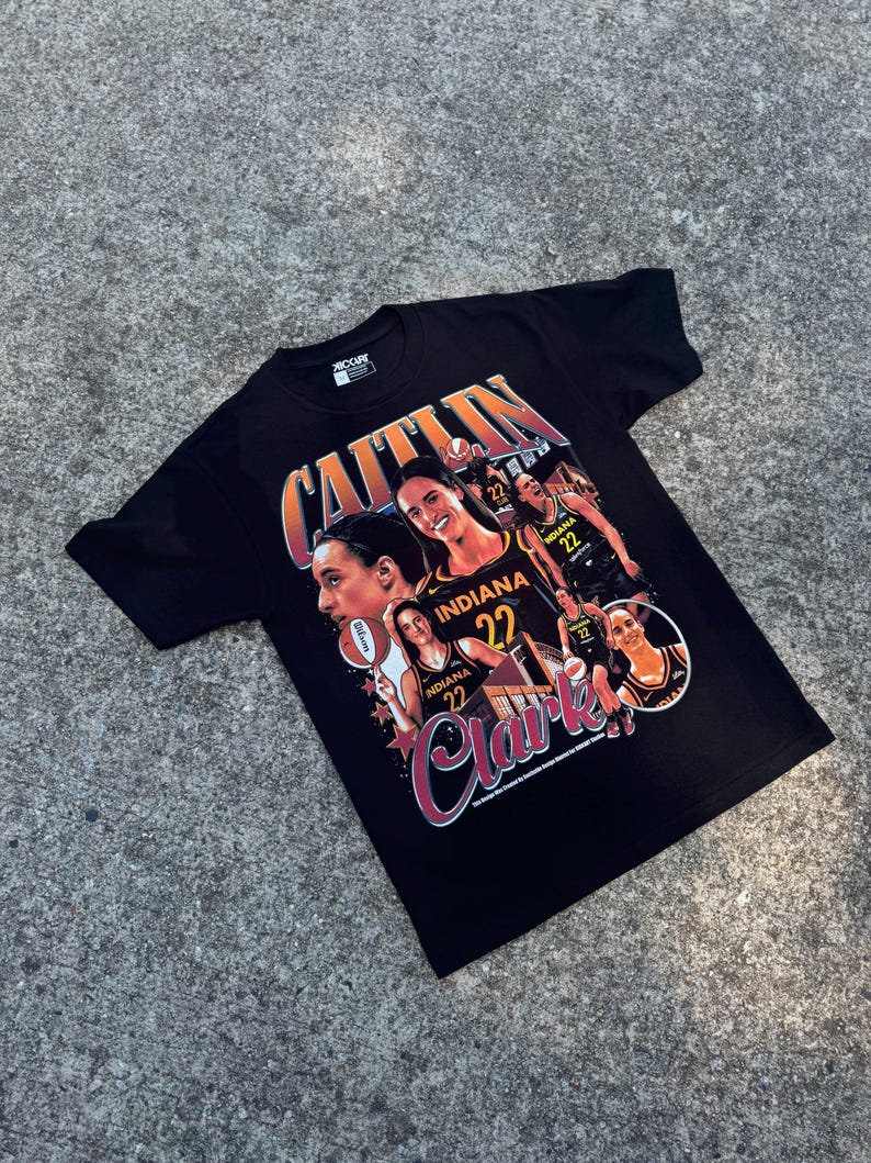 May include: Black t-shirt with a graphic print of a basketball player, Caitlin Clark, wearing a yellow and black Indiana Hoosiers jersey. The graphic includes multiple images of Clark in different poses, including dribbling a basketball and shooting a basket. The text "Caitlin Clark" is printed in a large, bold font.